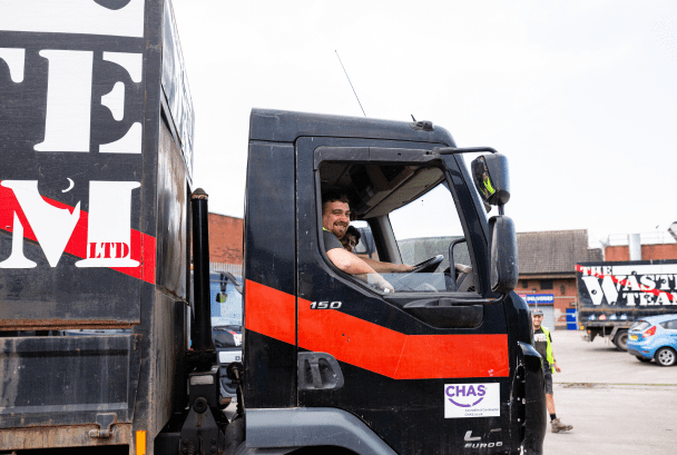 man looking out of the window of The Waste Team van and smiling