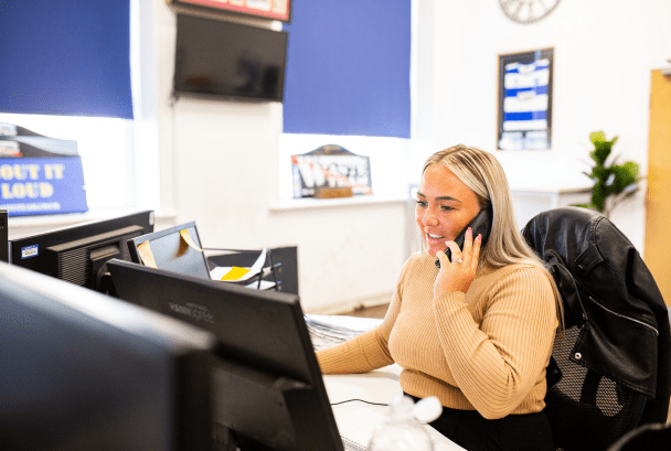Women on the phone with desktop screen in front of her in The Waste Team office