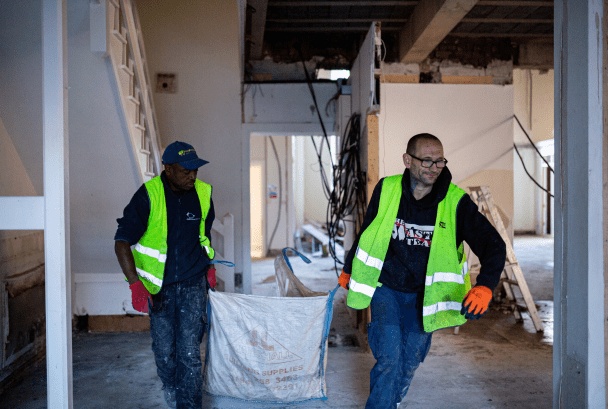 2 men in high vis jackets removing building waste from a building in need of a strip-out