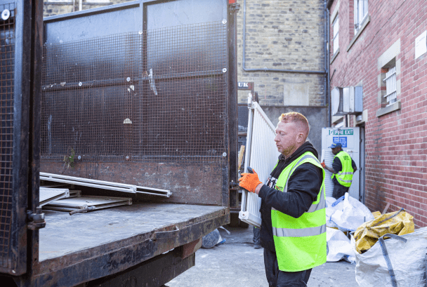 Man lifting old radiator into back of waste removal van