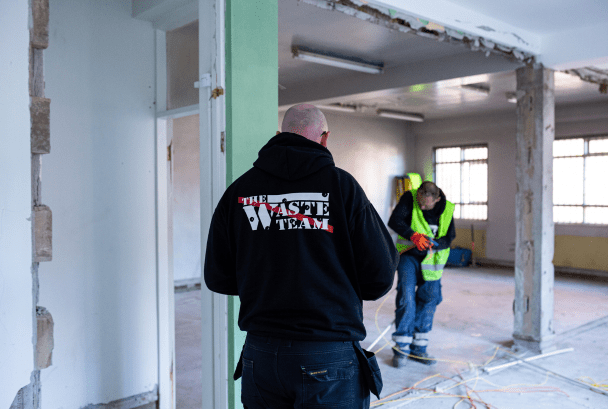 Two men in empty office building tackling waste removal