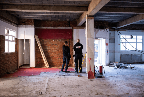 Building having strip out service photographed with two men assessing the works