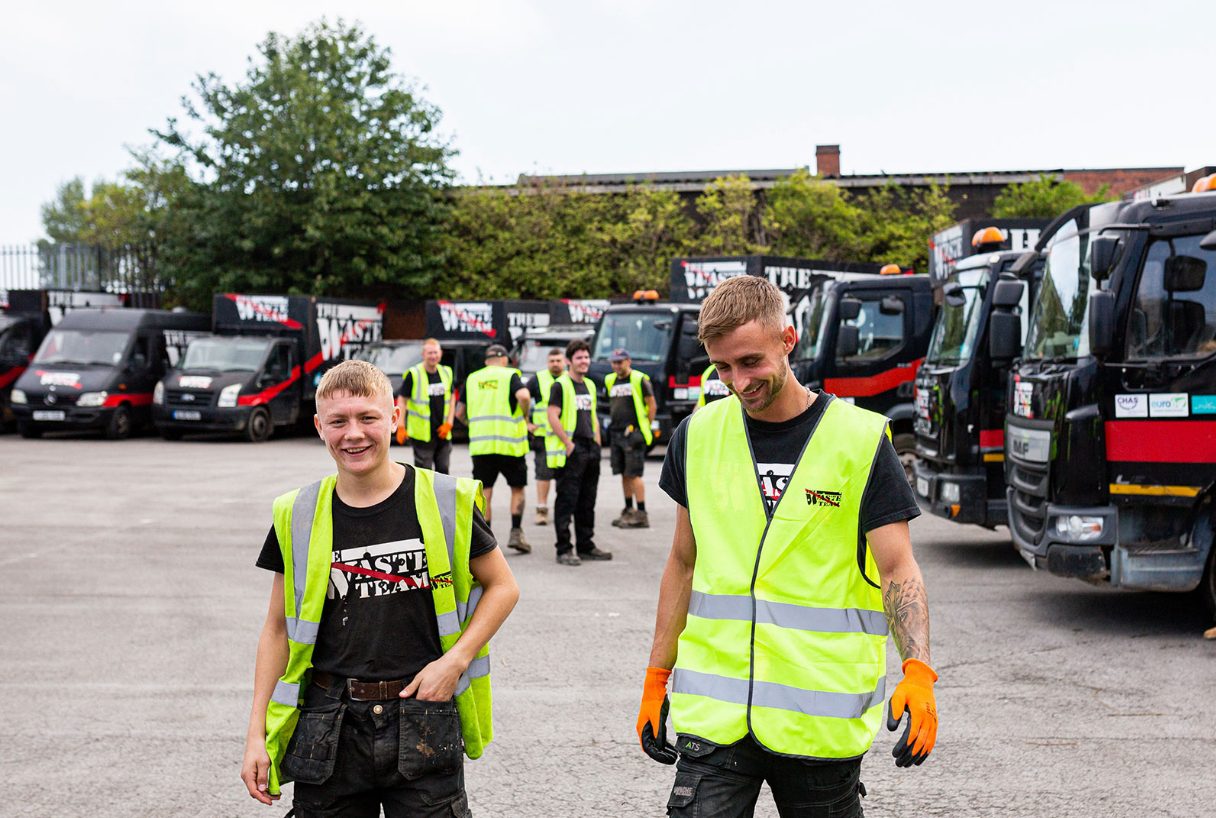 The Waste Team workers in high vis jackets walking away from waste vans