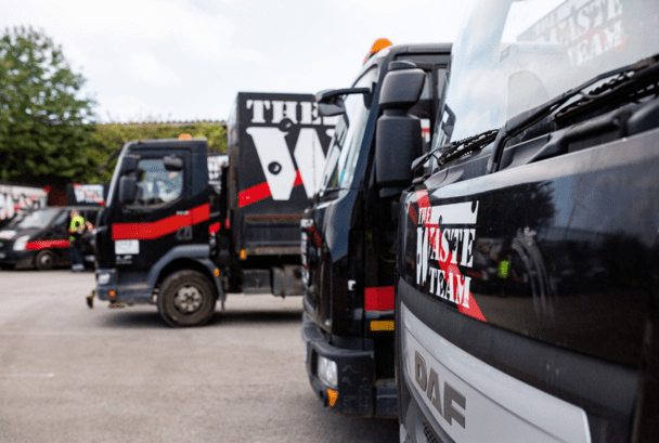 A row of parked mobile waste removal vans branded with The Waste Team logo