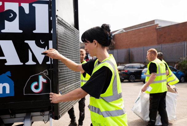 Women in high-vis closing the back of a mobile waste removal van