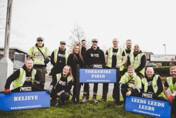 The Waste Team all in branded uniform standing in front of Leeds United based signs
