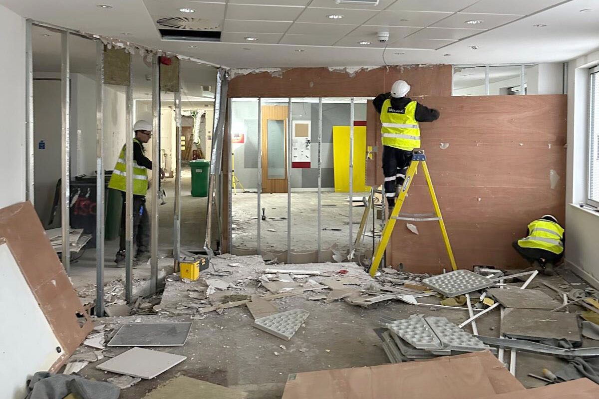Wide view of the inside of an office, waste team stripping out the inside