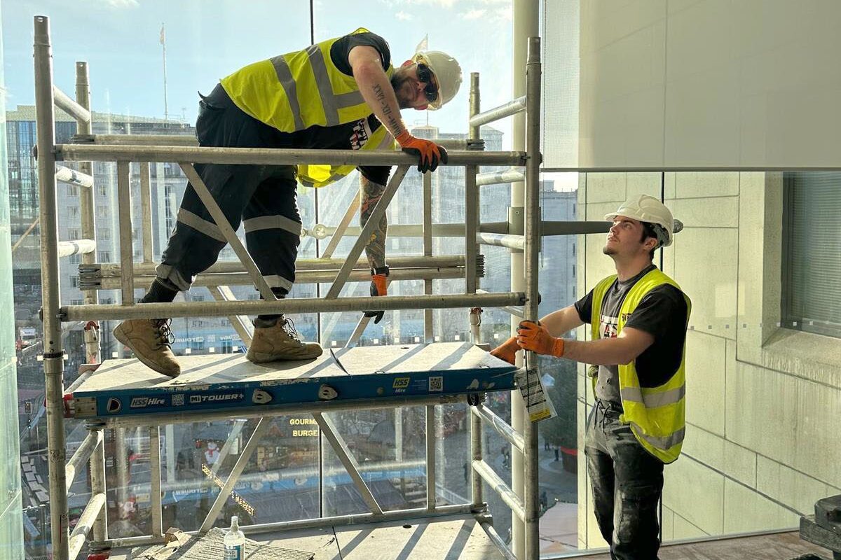 Twow aste team employees in high vis jackets, hrd hats, inside a building doing a strip out