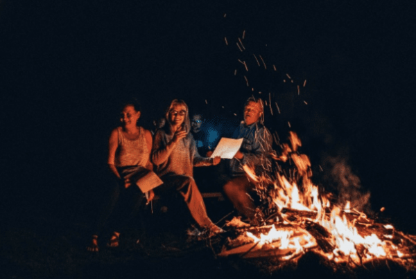 three women sat round a fire burning paper