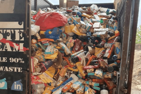 The waste team branded waste truck with open door piled high with biscuits still in packaging