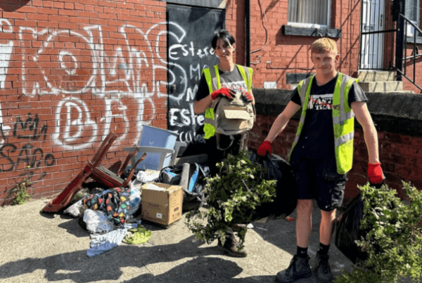 two workers in a fly tipped gravity yard clearing up the waste