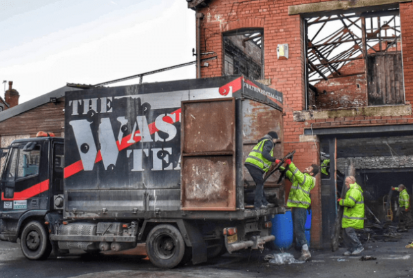 derelict building being stripped of waste by several workers in high vis jackets. Waste being put into the back of The Waste Team van.