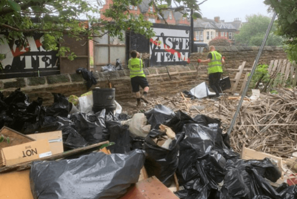 Household waste piled high with two men in high vis jackets loading into The Waste Team van