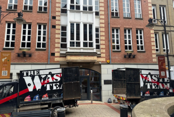 Two branded The Waste Team vans parked outside an office building in Leeds.