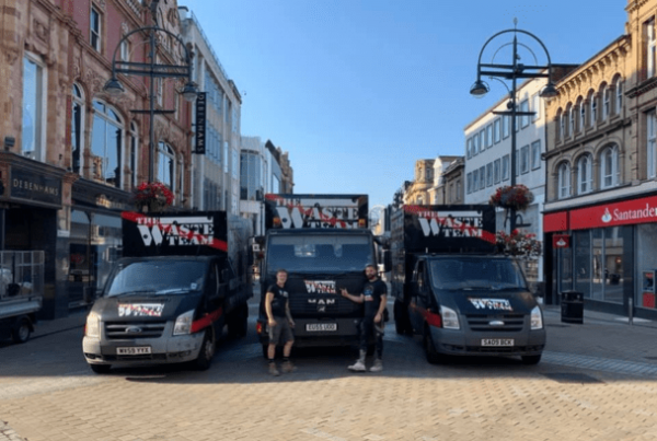 three The Waste Team waste vans lined up in a row in Leeds city centre with two male team members