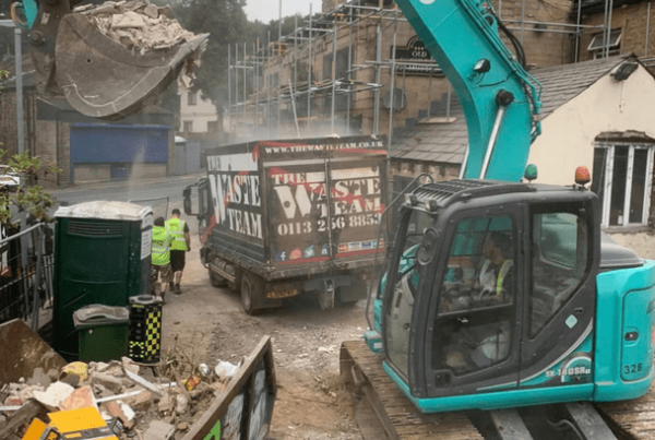 a diger and The Waste Team van outside a building site collecting commercial building waste