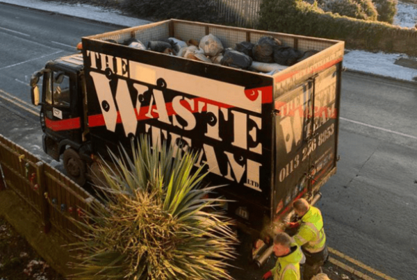 The Waste Team van parked on a housing estate street with two men loading waste into the back