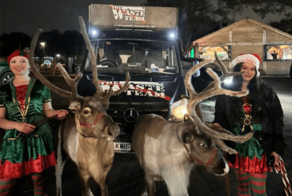 two women dressed as elves in front of the Waste Team van with two reindeers