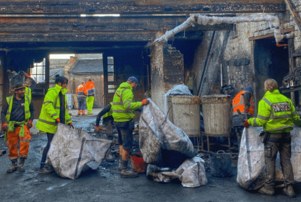 a group of workers in high vis jackets carrying rubbish bags and litter picking in the street